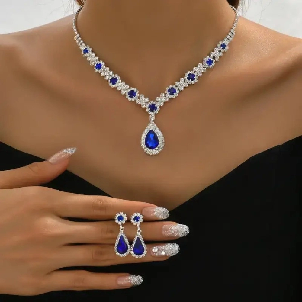 Silver-tone necklace with round and pear-shaped blue stones, worn with matching drop earrings