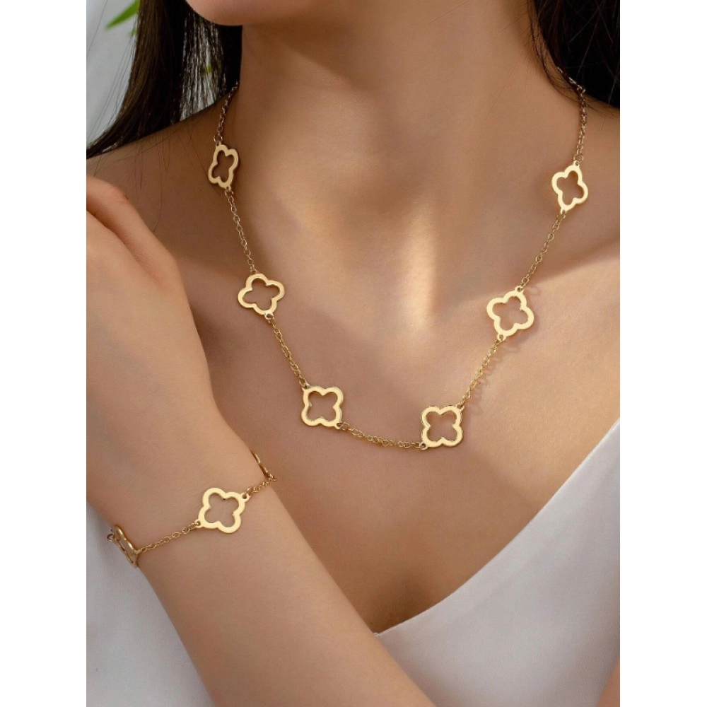 Model wearing a gold-tone station necklace with open clover motifs and a matching thin bracelet