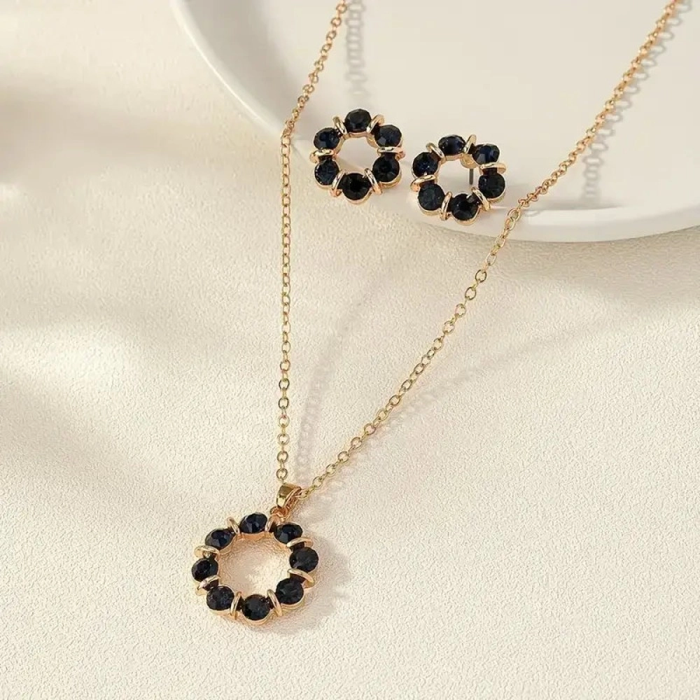 Gold-tone pendant and stud earrings formed from a circle of dark navy stones